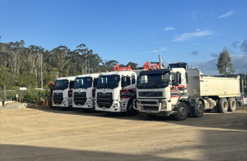 Work yard with Pavitt Group trucks parked in front of excavators and earthmoving machinery.