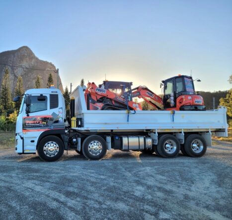 Pavitt Group truck transporting mini excavators to a Queensland civil construction site at sunrise.